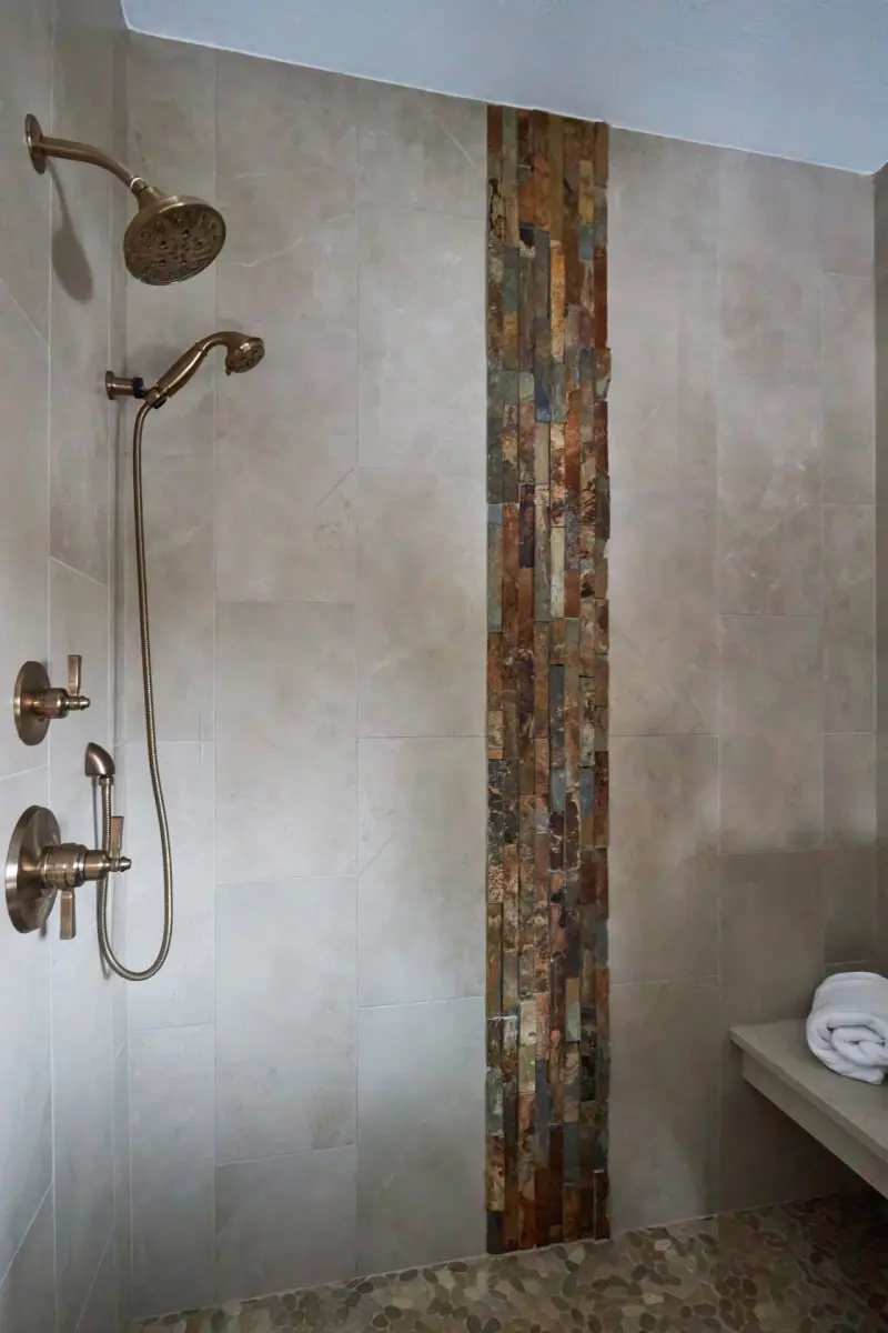 Grafton-Primary-Bath-4-rszd-scaled Grafton shower with light wall tile, a vertical accent strip in warm and gray tones, and a shower bench.