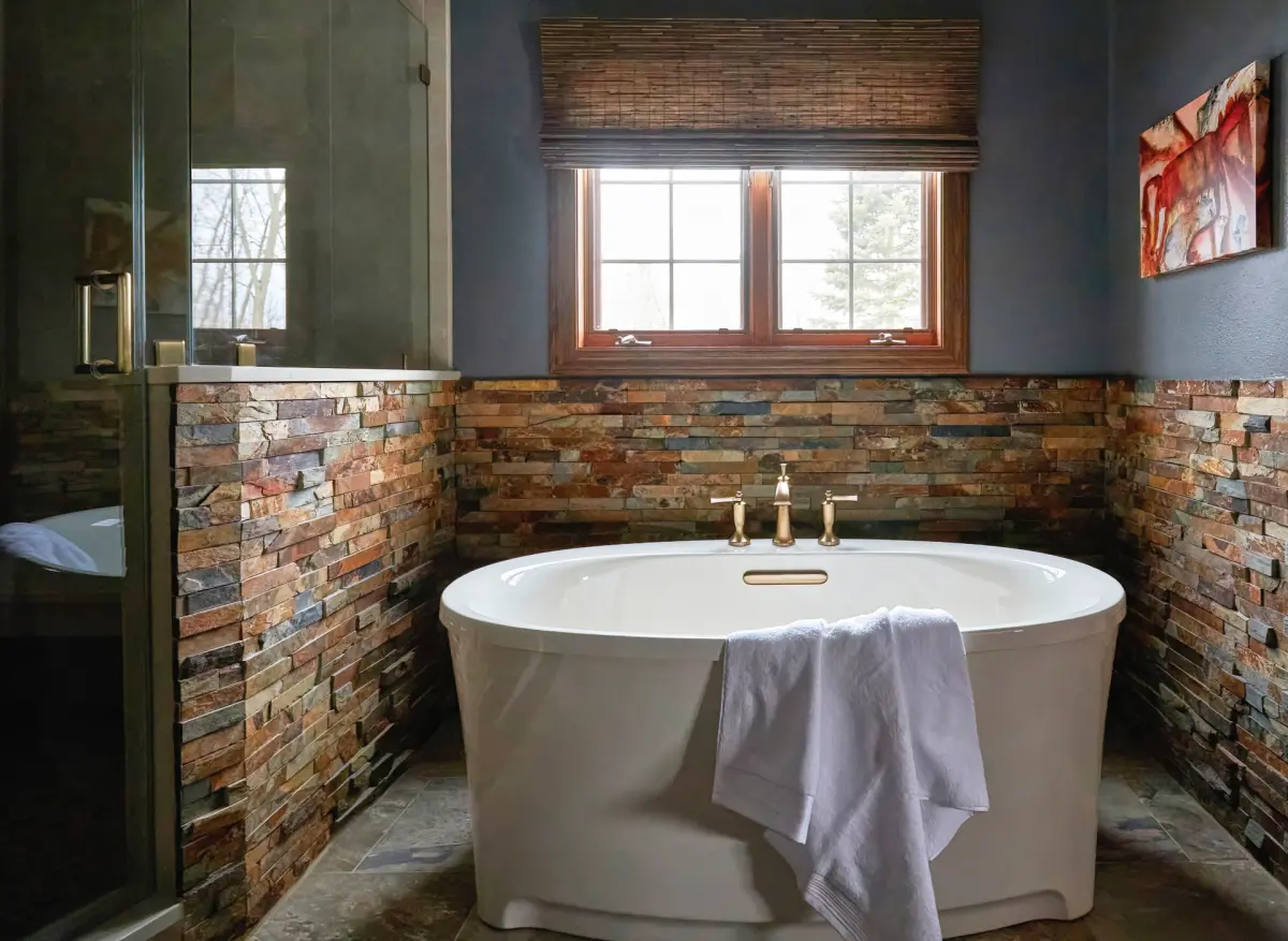 Grafton-Primary-Bath-6.revised-rszd-scaled Wood-toned double vanity with a tall center storage cabinet, light countertops, and blue-gray walls in Grafton.